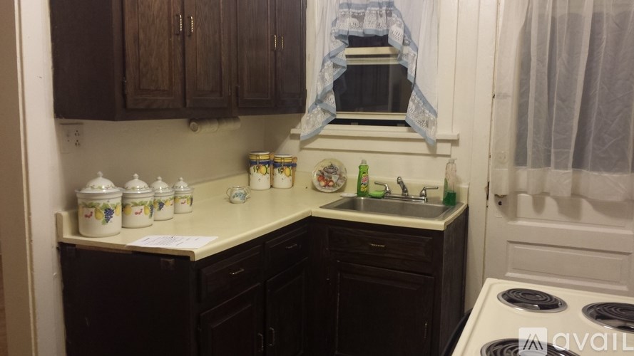 A kitchen with a stove, sink, and cabinets.