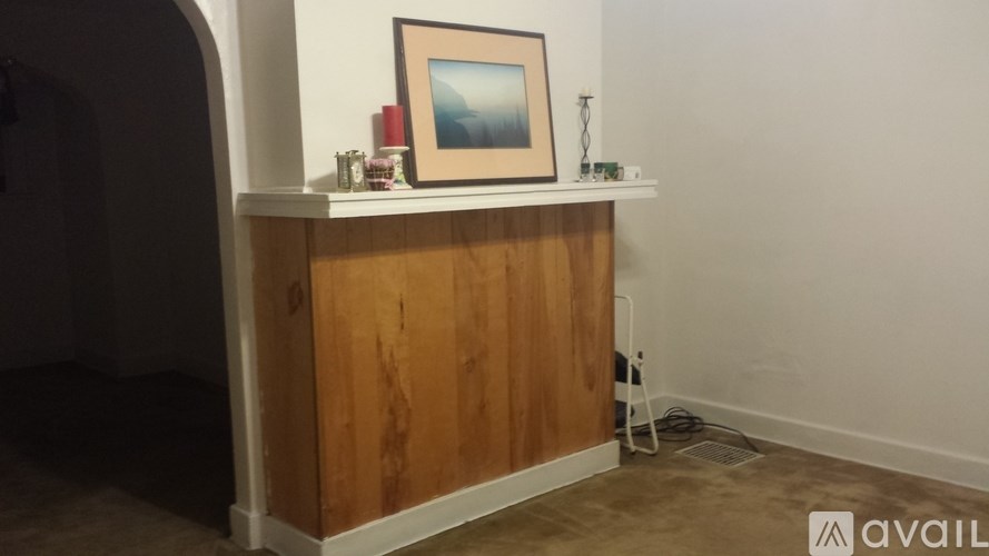 A wooden cabinet with a picture frame on top and a few items on the shelf.