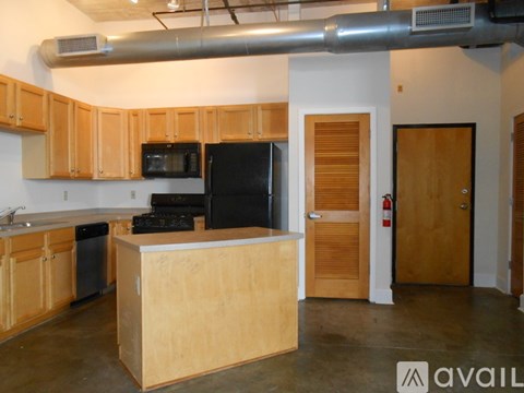 A kitchen with wooden cabinets and a black fridge.