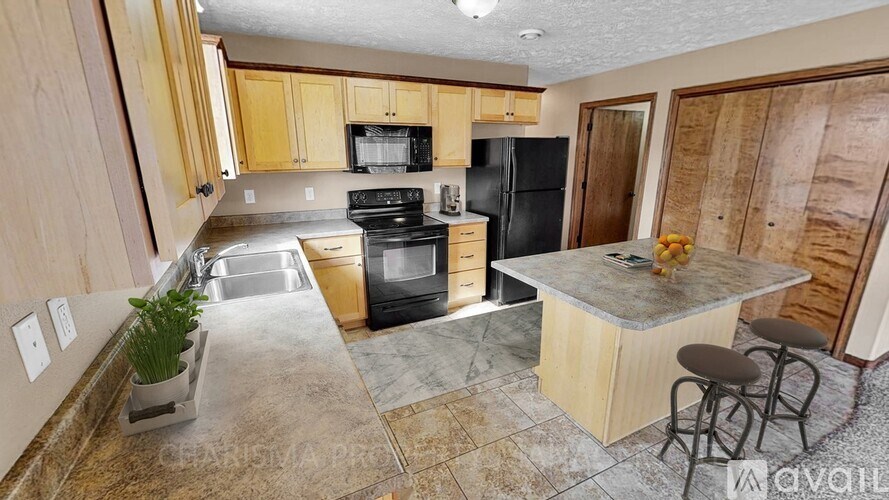 A kitchen with wooden cabinets and a black refrigerator.