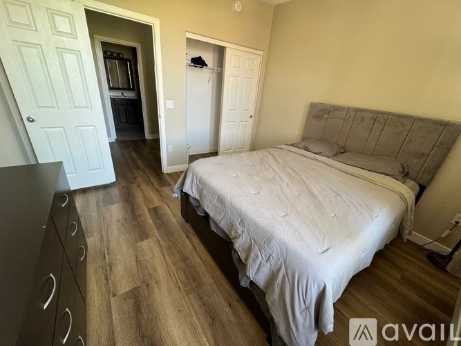 A bedroom with a large bed and a wooden floor.