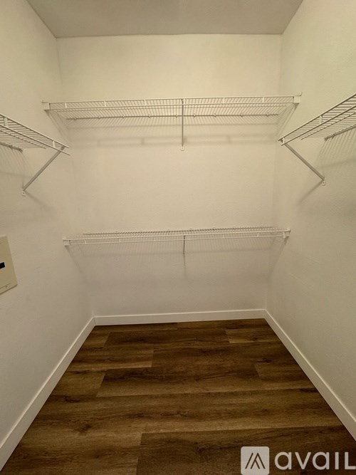 Empty walk-in closet with shelves and wooden floors.
