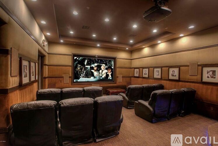 A home theater with a row of black leather chairs facing a large screen.