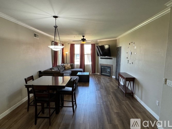 A living room with a dark wood floor and a large window with red curtains.