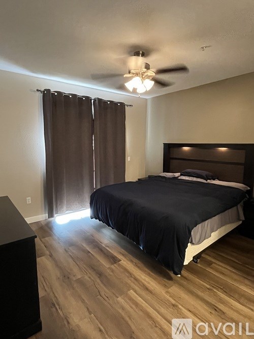 A bedroom with a bed, dresser, and ceiling fan.