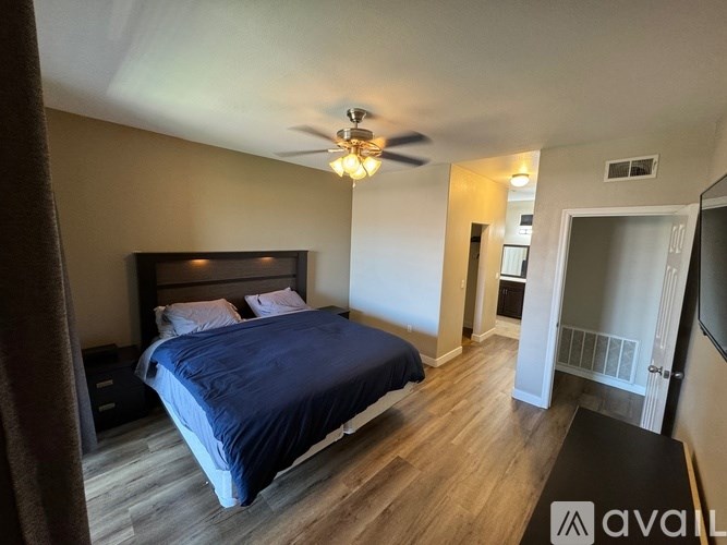 A bedroom with a bed, dresser, and ceiling fan.