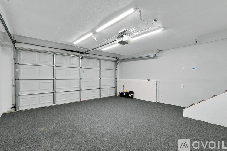 A spacious garage with a white door and a grey carpeted floor.
