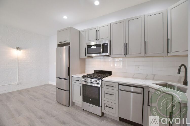 A kitchen with a refrigerator, microwave, oven, and sink.