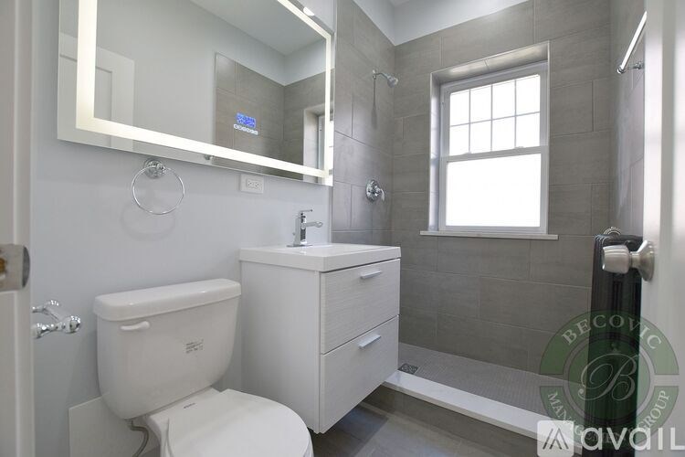 A bathroom with a toilet, sink, and mirror.