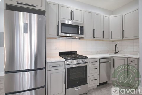 A kitchen with a stainless steel refrigerator and white cabinets.