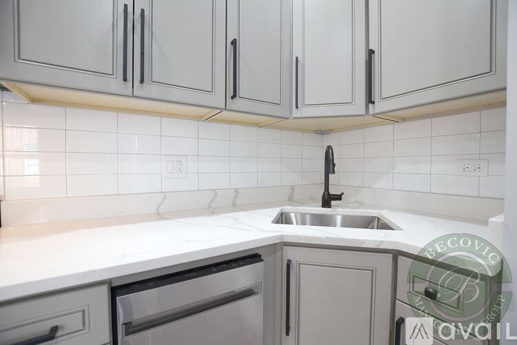 A kitchen with white cabinets and a marble countertop.