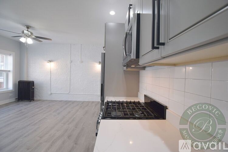 A modern kitchen with a fan, stove, and cabinets.