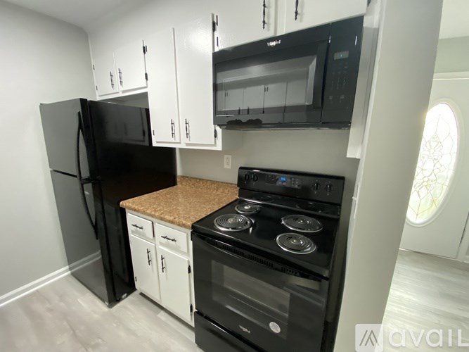 A black fridge and oven in a kitchen with white cabinets.