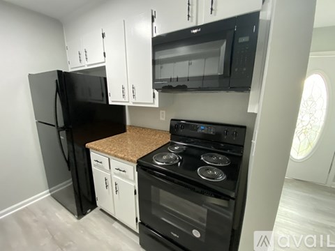 A black fridge and oven in a kitchen with white cabinets.