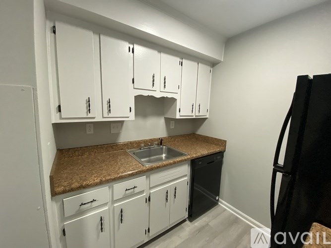 A kitchen with white cabinets and a black refrigerator.