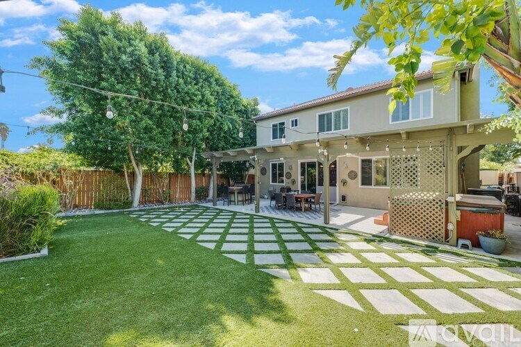 A backyard with a green lawn and a white and green patterned area.