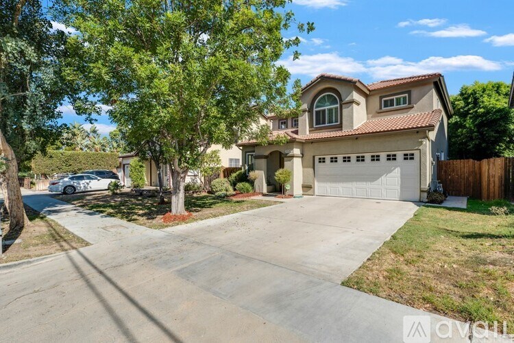 A house with a garage is surrounded by trees and has a driveway.