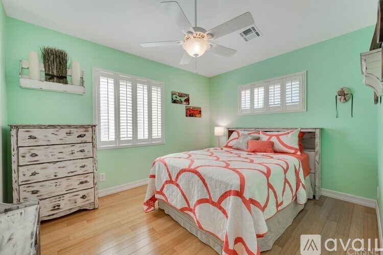A bedroom with a bed, dresser, and ceiling fan.
