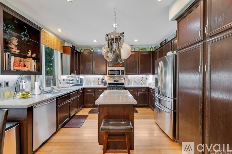 A modern kitchen with dark wood cabinets and stainless steel appliances.
