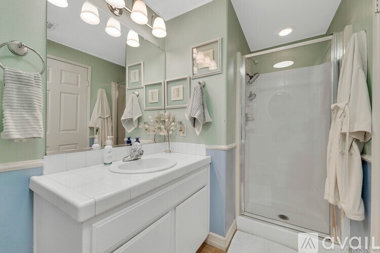 A bathroom with a white sink and a glass shower door.