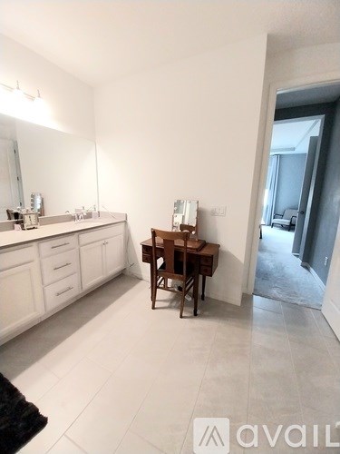 A bathroom with a sink, mirror, and a wooden chair.