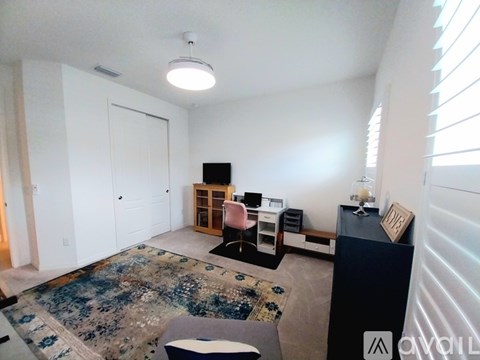 A living room with a rug, a sofa, a table with a lamp and a picture frame on it, and a cabinet with a TV on top.