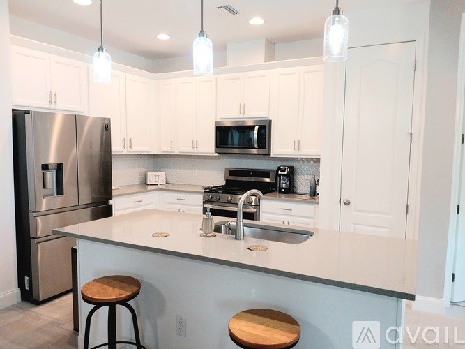 A kitchen with white cabinets and a stainless steel refrigerator.