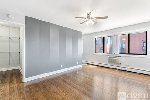 A room with a ceiling fan and a window overlooking a city.