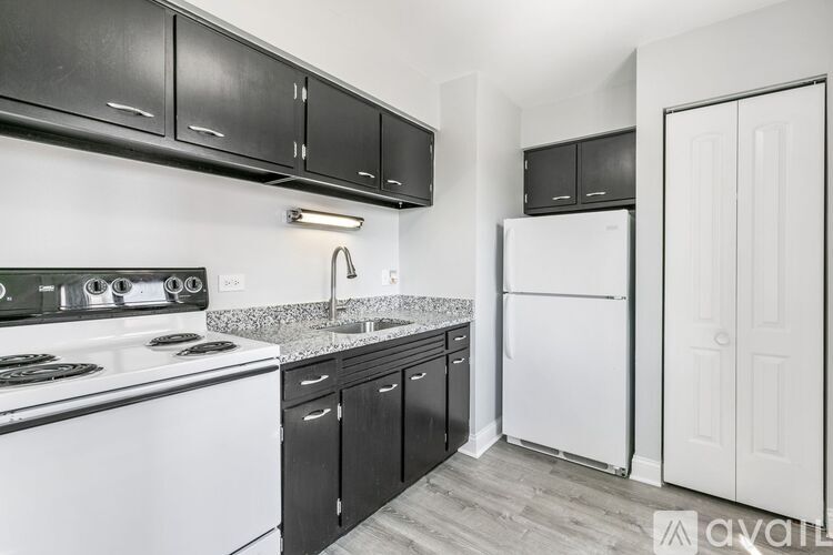 A kitchen with black cabinets and a white refrigerator.