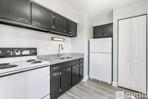 A kitchen with black cabinets and a white refrigerator.