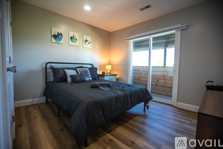 A bedroom with a bed, nightstand, and a window overlooking a balcony.