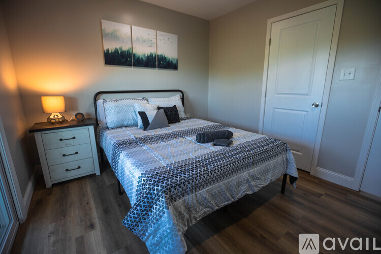 A bedroom with a bed, nightstand, and lamp.