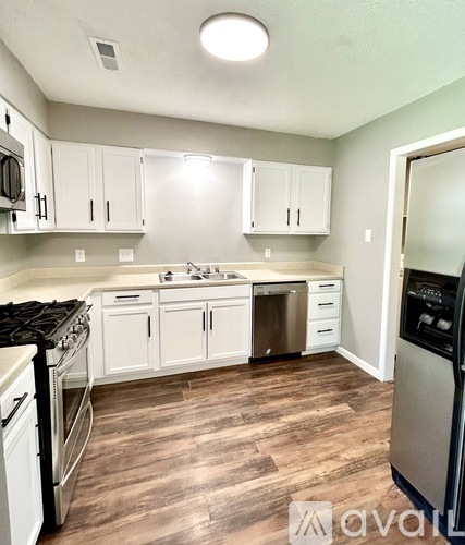A kitchen with white cabinets and a wood floor.