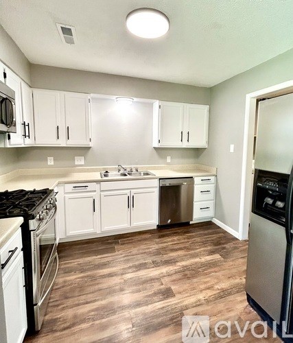 A kitchen with white cabinets and a wood floor.