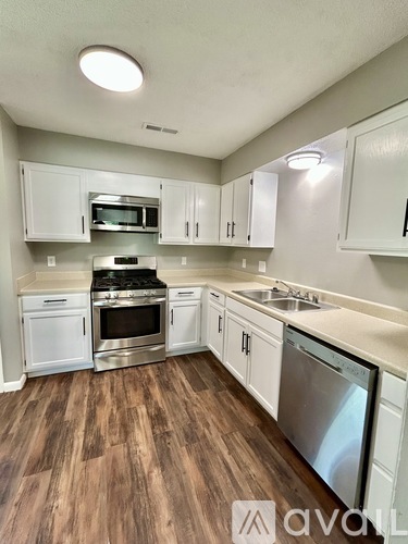 A kitchen with white cabinets and a wooden floor.