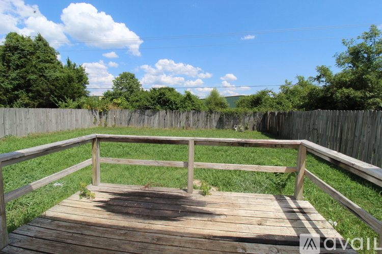 A wooden deck with a railing overlooking a grassy area.