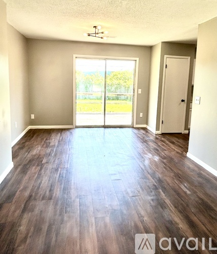A room with wooden floors and a sliding glass door leading outside.