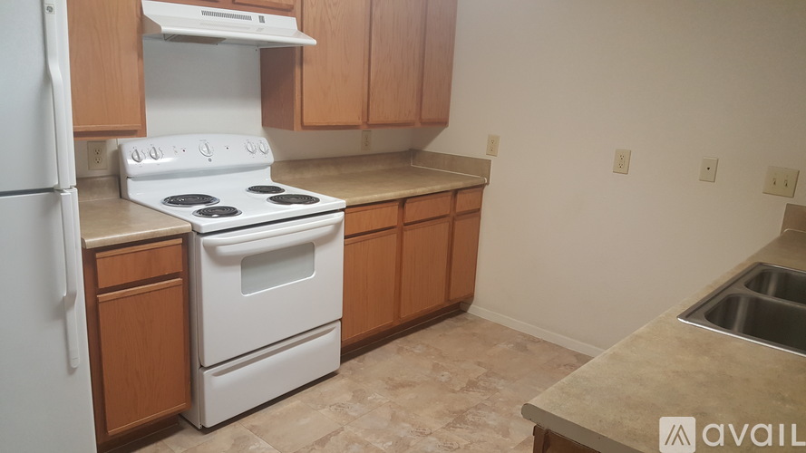 A kitchen with a white stove and wooden cabinets.