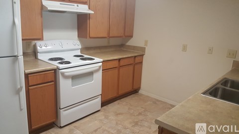 A kitchen with a white stove and wooden cabinets.