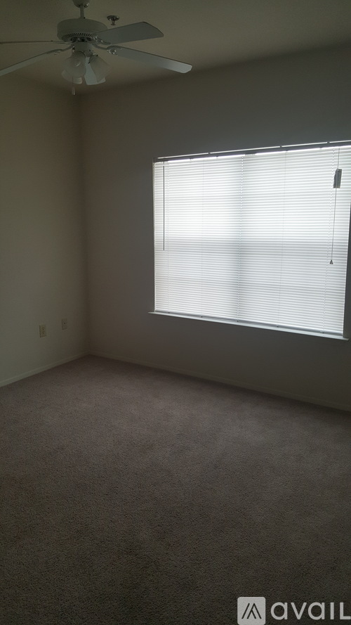 A room with a ceiling fan and a window with blinds.