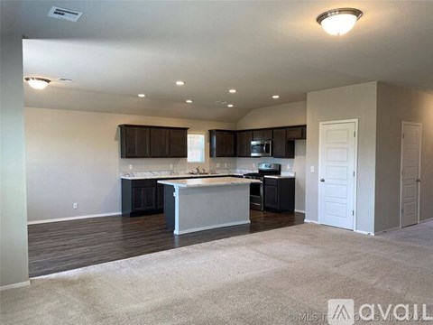 A spacious kitchen with dark brown cabinets and a white island.