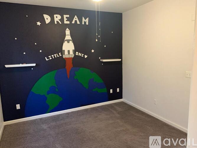 A room with a wall mural of a rocket ship and the word "Dream" above it.