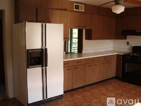 A white refrigerator in a kitchen with wooden cabinets.