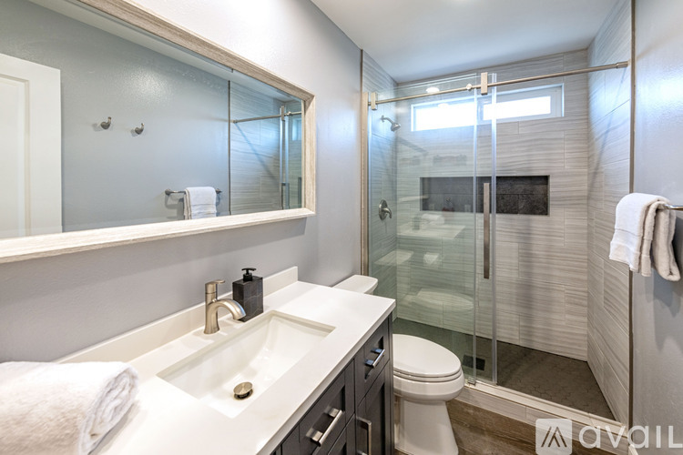 A modern bathroom with a white sink and a walk-in shower.