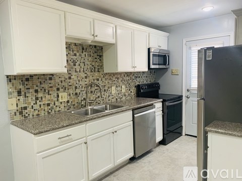A kitchen with white cabinets and a granite countertop.