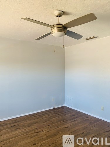 A room with a ceiling fan and wooden flooring.