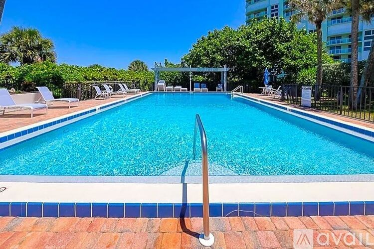 A pool with a diving board and lounge chairs.