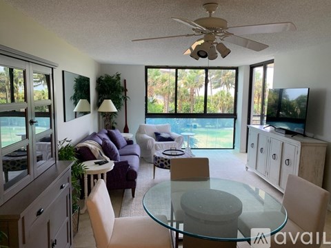 A living room with a glass table and a ceiling fan.