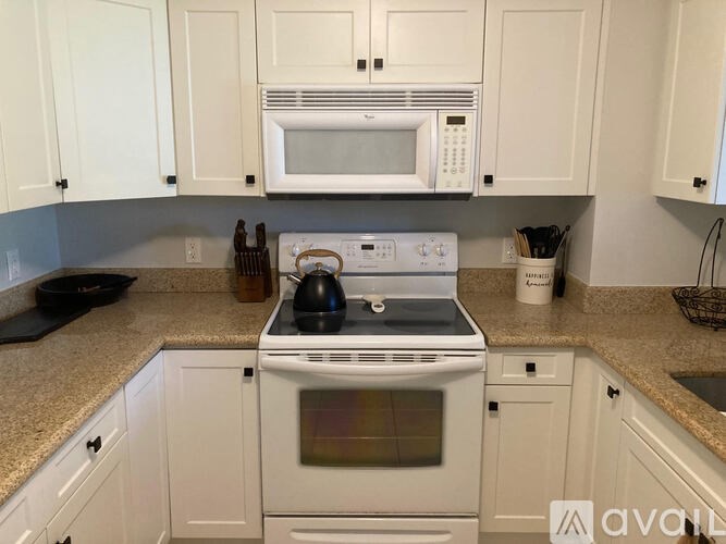 A white stove and microwave in a kitchen with white cabinets.