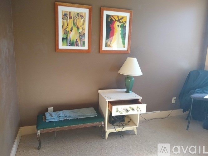 A room with a bed, a nightstand and two pictures on the wall.